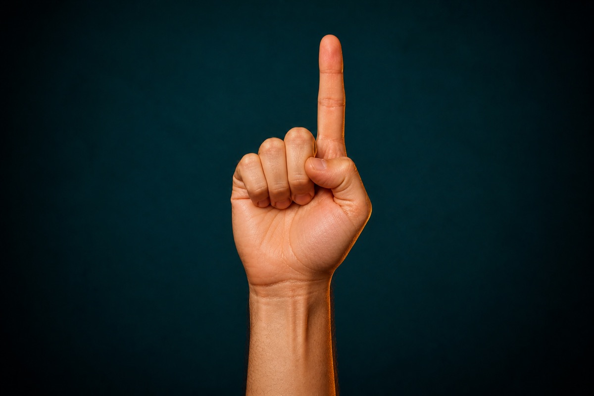 Left hand with one index finger raised against a dark teal studio background